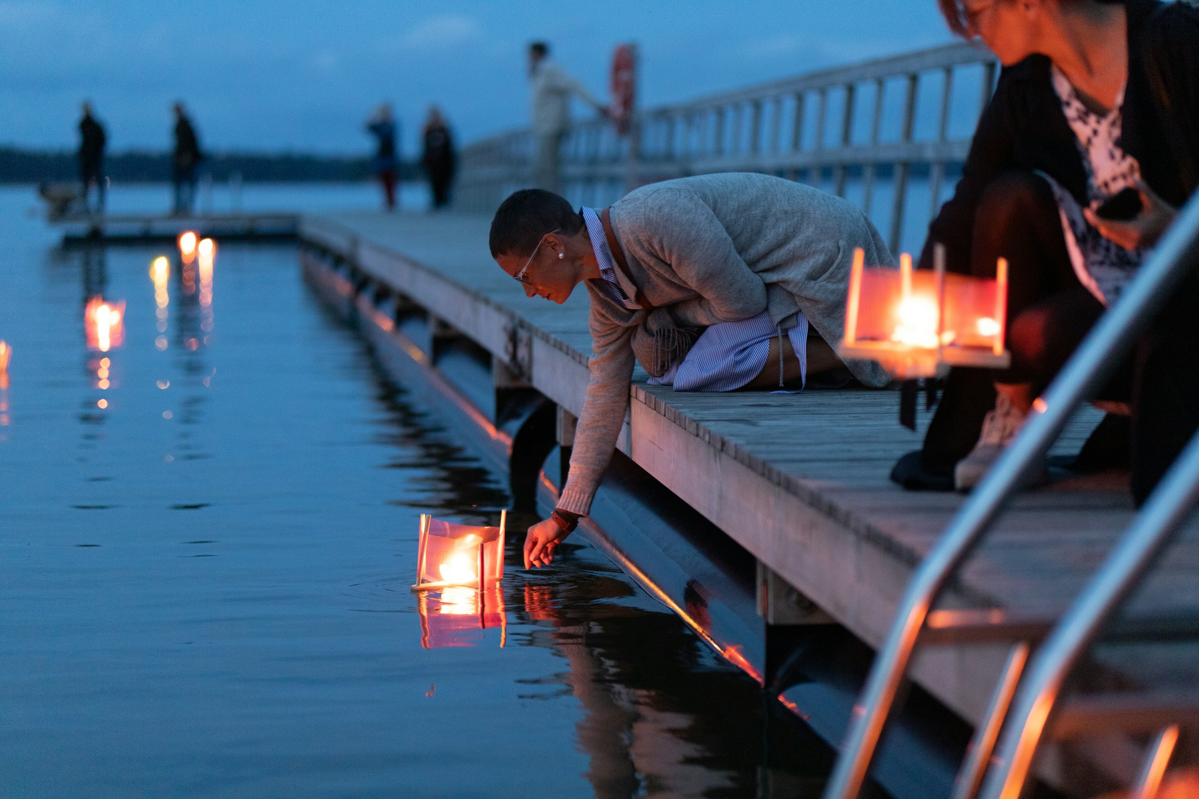 image of someone placing a floating lantern on water - image by oliver hotakainen - unsplash